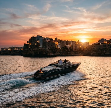 Luxury private boat Azzurro Vita cruising at sunset in front of Polignano a Mare old town cliffs