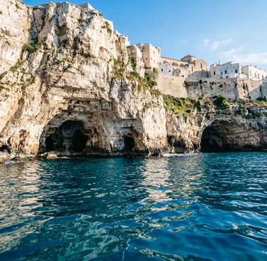 View from the sea of dramatic white limestone cliffs with cave openings and whitewashed buildings above