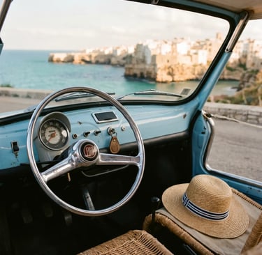 Sky-blue vintage Fiat 500 Spiaggina dashboard and straw hat with Polignano coastline in background