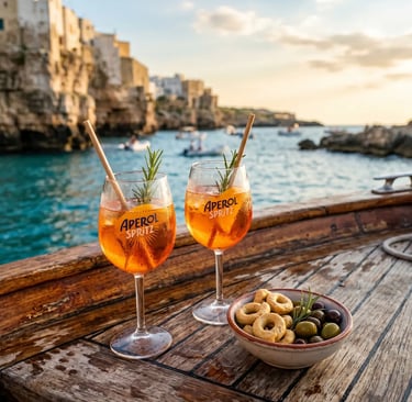 Two Aperol Spritz glasses and taralli on wooden boat deck overlooking Puglia coast