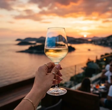 Hand holding Croatian white wine glass against Adriatic sunset over Elaphite Islands Dubrovnik