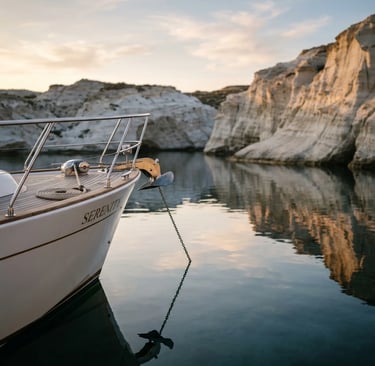 Bow of luxury yacht anchored in calm volcanic cove at sunset in Milos Greece