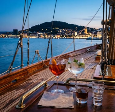 Cocktail glasses on polished sailboat deck with Split Croatia city lights at blue hour