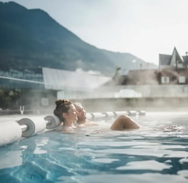 A couple relaxing in the outdoor thermal infinity pool at Aqua Dome spa in Sölden, Austria, surround