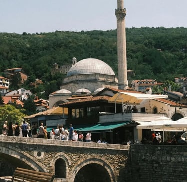 Ottoman mosque minaret rising above stone bridge and bazaar in historic Prizren Kosovo