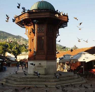 Ottoman wooden Sebilj fountain in Baščaršija square Sarajevo surrounded by flying pigeons