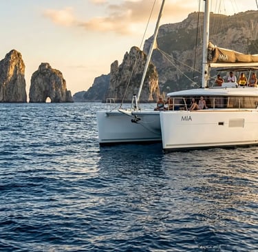 Catamaran anchored near Capri Faraglioni rocks at sunset during private yacht tour