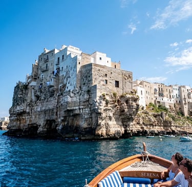 Dramatic white limestone cliffs of Polignano a Mare seen from wooden boat on blue Adriatic Sea