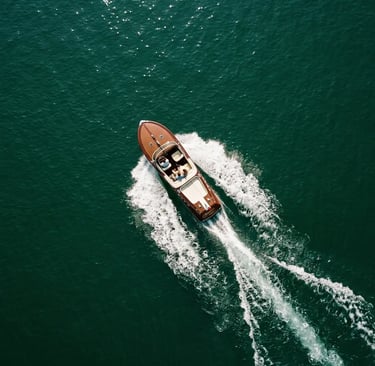 Aerial drone view of vintage mahogany boat cutting through emerald Lake Como waters