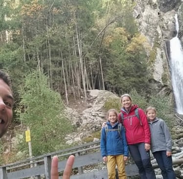 Happy family taking a selfie by a scenic alpine waterfall during a nature walk on a Chamonix guided 