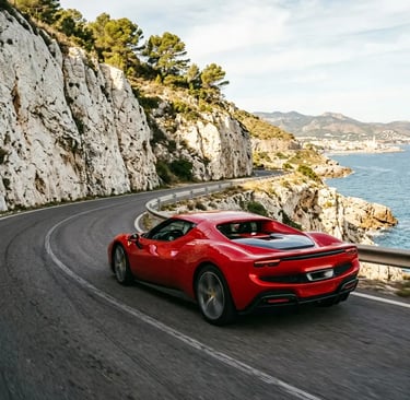 Ferrari 296 GTB cornering on a Garraf Massif coastal road near Barcelona