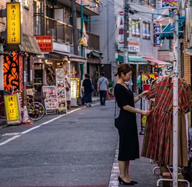 Young woman browsing vintage clothing on a colorful street in Shimokitazawa, Tokyo, surrounded by sm