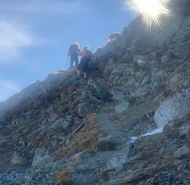 Hikers navigate a steep rocky ridge toward the sun during a sunrise tour in Innsbruck.