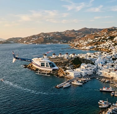 Private helicopter approaching Mykonos coastline with iconic windmills at golden hour