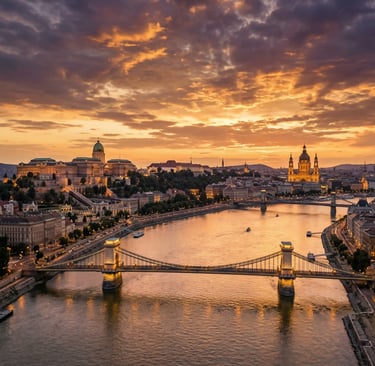 Aerial view of Budapest at sunset with Chain Bridge, Danube River, and Buda Castle glowing orange