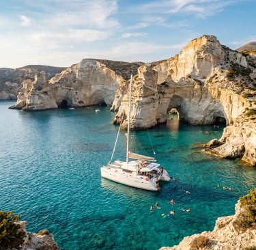 White catamaran anchored at Kleftiko Milos with swimmers in turquoise water below white cliffs