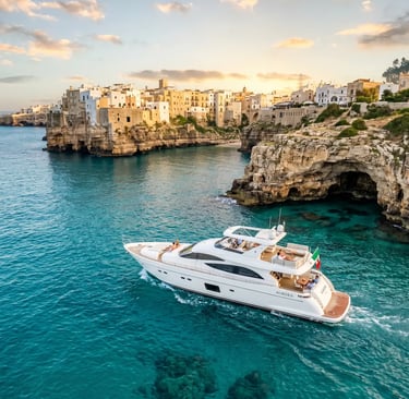 Luxury white yacht Aurora cruising turquoise Adriatic waters below Polignano a Mare cliffs