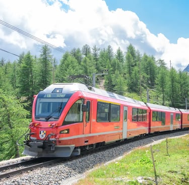 Red Bernina Express train heading to St. Moritz through green summer alpine forest