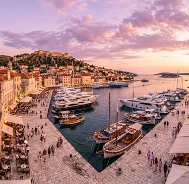 Hvar Town harbor at sunset with luxury yachts and Spanish Fortress on the hill