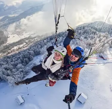 Happy couple taking a selfie while tandem paragliding over snowy Interlaken trees