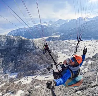 Top-down view of tandem paragliders flying over a frozen forest in Jungfrau Region