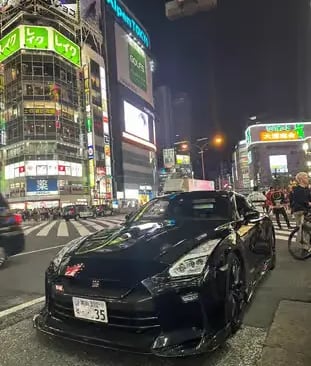Black Nissan GT-R cruising neon streets of Shibuya, Tokyo.