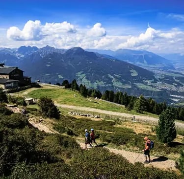 Hikers on a scenic mountain trail overlooking Innsbruck valley and Alps..