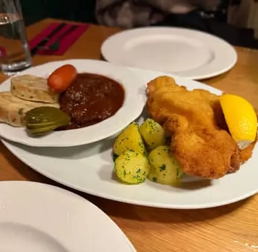 A plate of Wiener Schnitzel, beef goulash, and parsley potatoes.