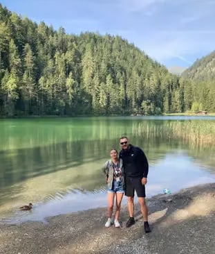 Couple posing on the shore of an emerald green lake with dense pine forest in Ehrwald Tyrol