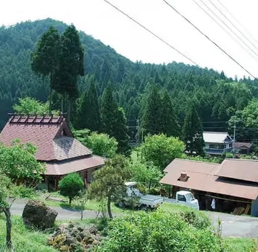 Traditional Japanese farmhouse nestled in a forested mountain valley in rural Kyoto