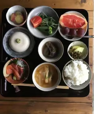 Traditional Japanese farm-to-table meal served on a black tray with multiple small dishes