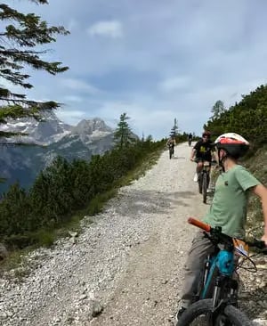Cyclists riding gravel path on guided e-bike tour through the Italian Dolomites