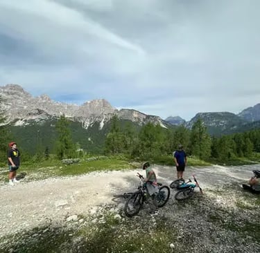 Small group of cyclists resting on mountain gravel trail with Dolomite peaks