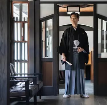 Man in elegant black hakama standing in traditional Japanese interior doorway Kyoto