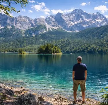 Man standing at Eibsee shore looking toward Zugspitze mountains, Bavaria