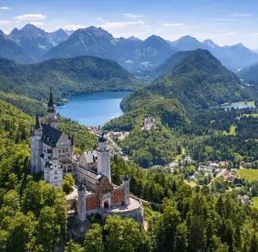 Aerial view of Neuschwanstein Castle surrounded by green Alps and lakes