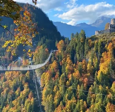 Highline 179 suspension bridge over autumn forest with castle ruins, Austria