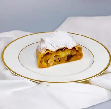 A single slice of traditional homemade Apple Strudel generously dusted with powdered sugar served on an elegant plate