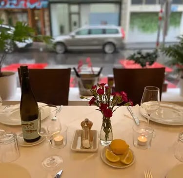 A set table with wine bottle, wine glasses, candles and fresh flowers prepared for guests at a Vienna cooking class