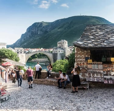 Tourists walking cobblestone streets near Stari Most bridge and souvenir stalls in Mostar Bosnia