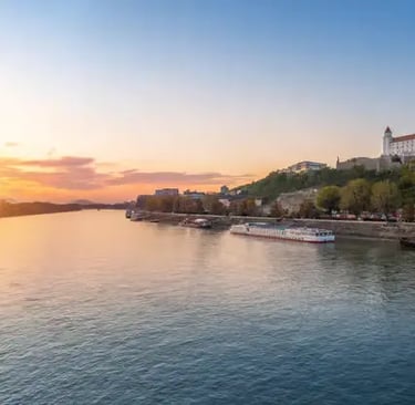 Panoramic sunset view of Bratislava Castle above the Danube River with cruise ship