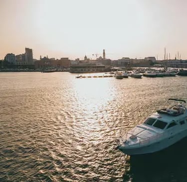 Bari harbor at sunset with boats and city skyline reflecting on calm Adriatic water