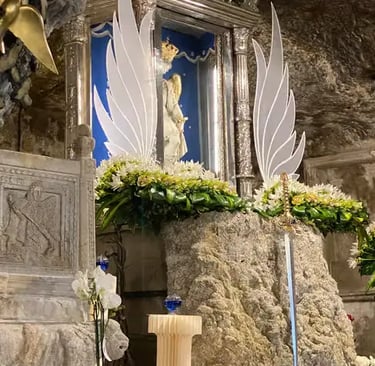 Madonna statue with white angel wings and flowers inside sacred grotto shrine