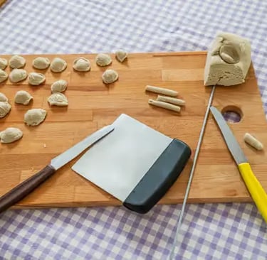 Freshly shaped orecchiette pasta with dough and knives on board at Lecce cooking class