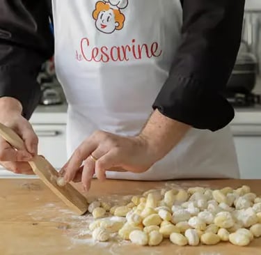 Cesarine chef hands rolling fresh gnocchi on wooden board during Lecce pasta cooking class