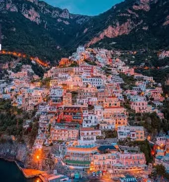 Positano colorful hillside houses illuminated at dusk seen from the sea