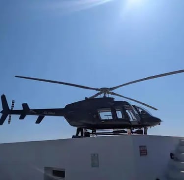 Private charter helicopter parked on rooftop helipad under clear Aegean blue sky