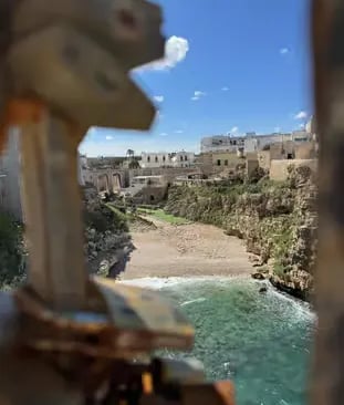Lama Monachile beach cove in Polignano a Mare seen through bridge love locks