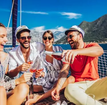 Four friends laughing and enjoying complimentary drinks on a boat tour along the Amalfi Coast