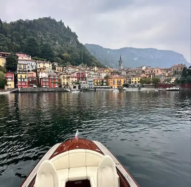 Wooden boat bow view approaching colorful Varenna village on Lake Como Italy